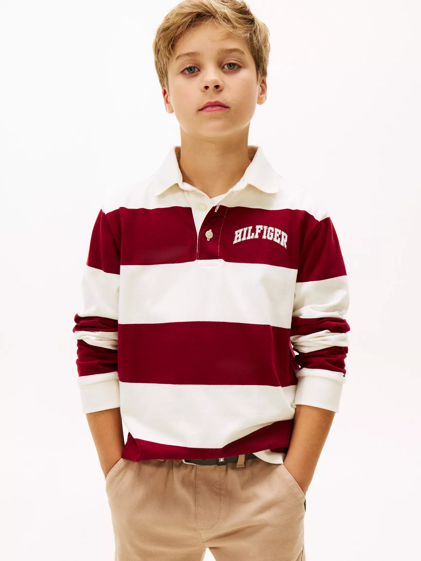 Child wearing a red and white striped polo shirt with 'Tommy Hilfiger' branding